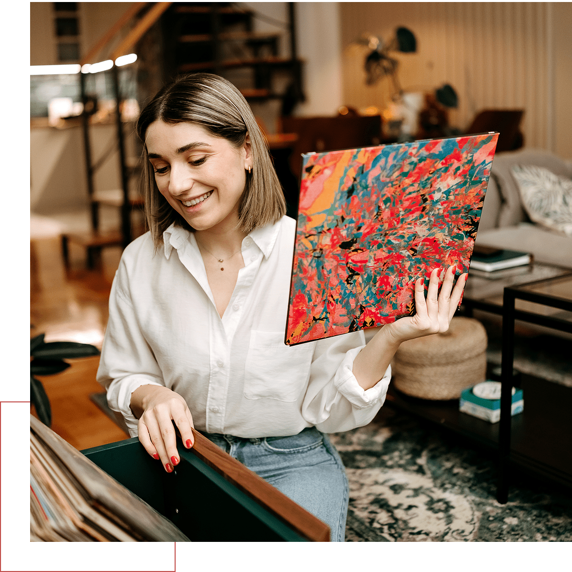 Woman holding colorful abstract painting, smiling indoors.
